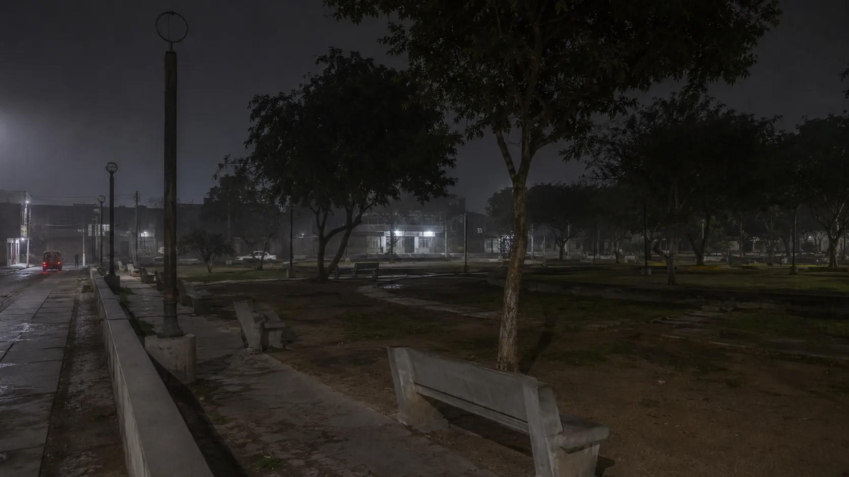 Parque municipal con árboles, bancas y senderos durante la noche