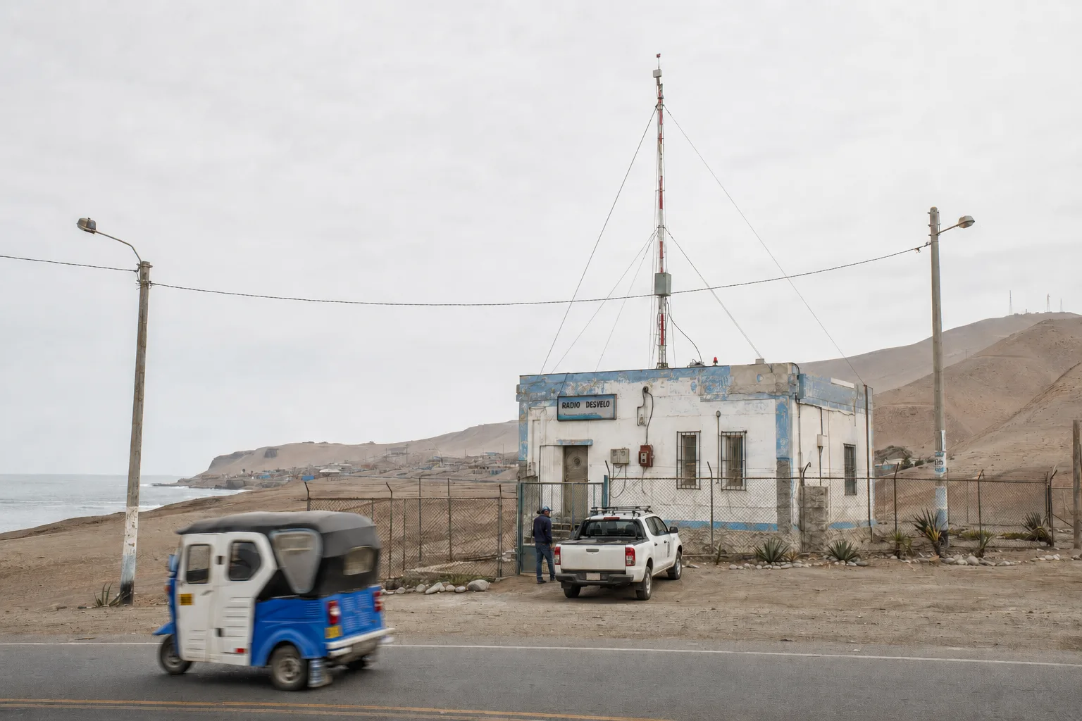 Edificio de la antigua estación Radio Desvelo con una antena alta junto a la costa